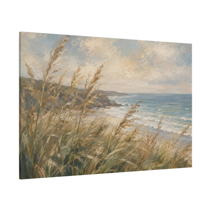 A square canvas wall art print depicting a coastal seascape with golden beach grass in the foreground, rocky shoreline, blue ocean water, and a cloudy sky, shown at an angle on a white background.