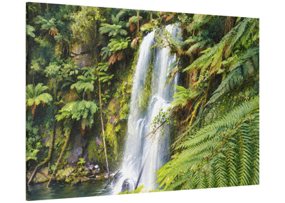 A rectangular canvas wall art print showing a lush tropical waterfall scene with dense green ferns and mossy rocks, photographed against a plain white background.