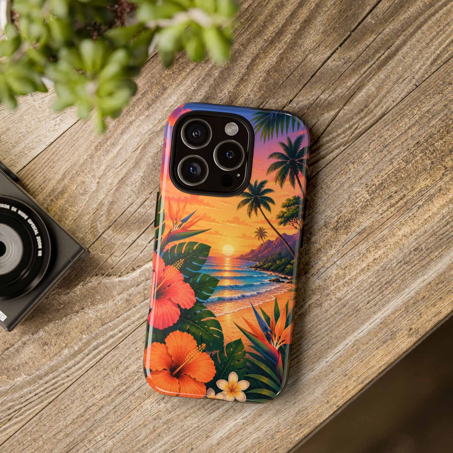 Phone case with tropical design on a wooden surface next to a camera